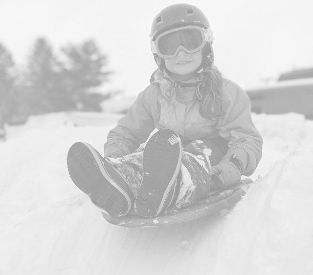 Girl sitting on a sled at top of hill